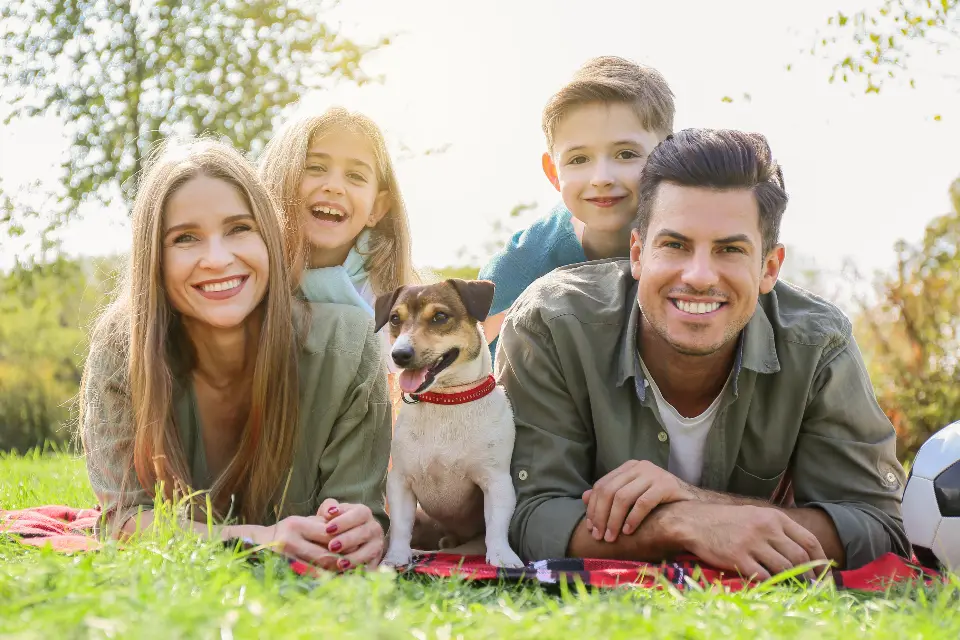 A family of four lying on the grass together with their dog, laughing